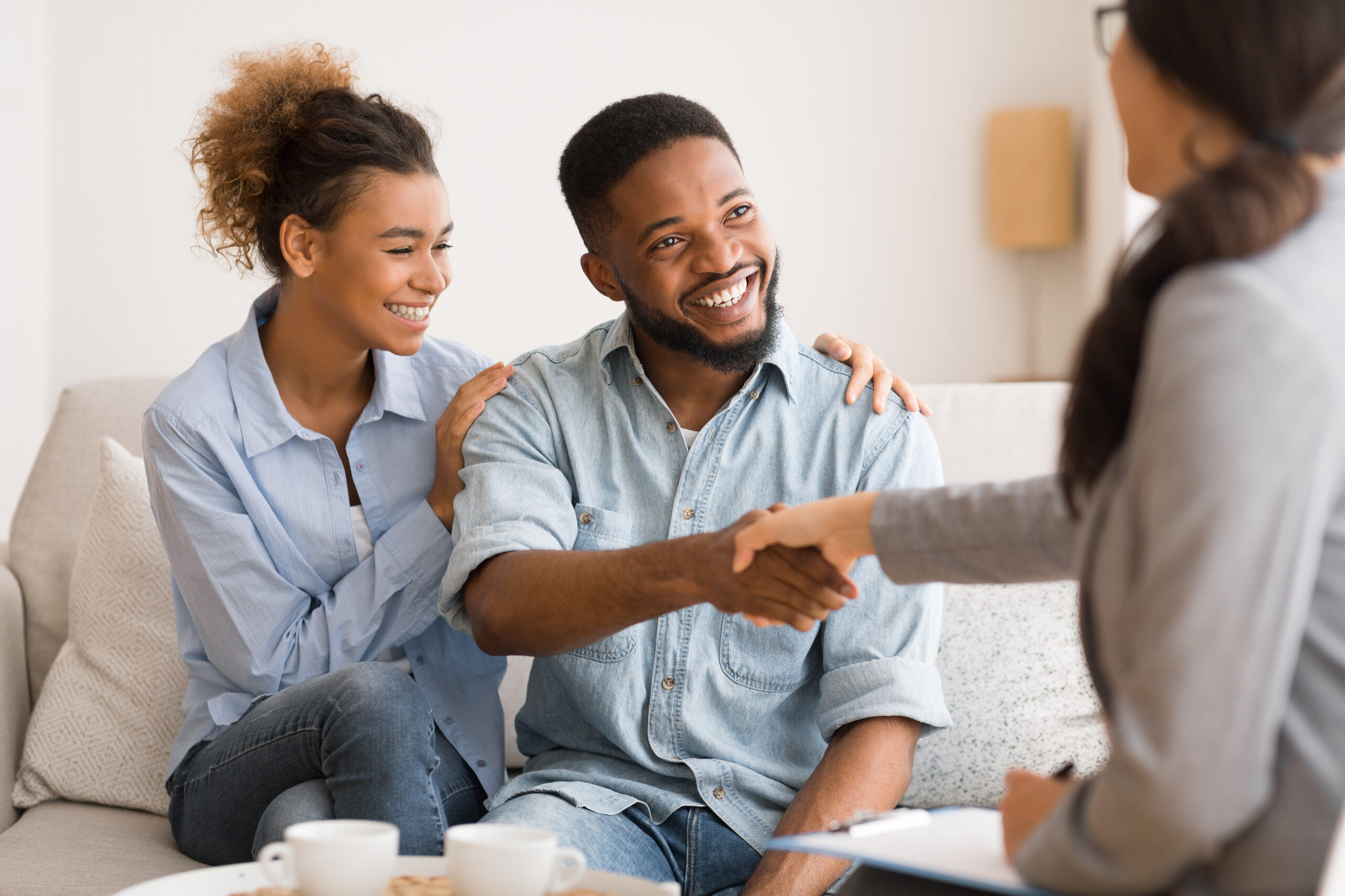 A couple smiles as they engage in a handshake with a counselor