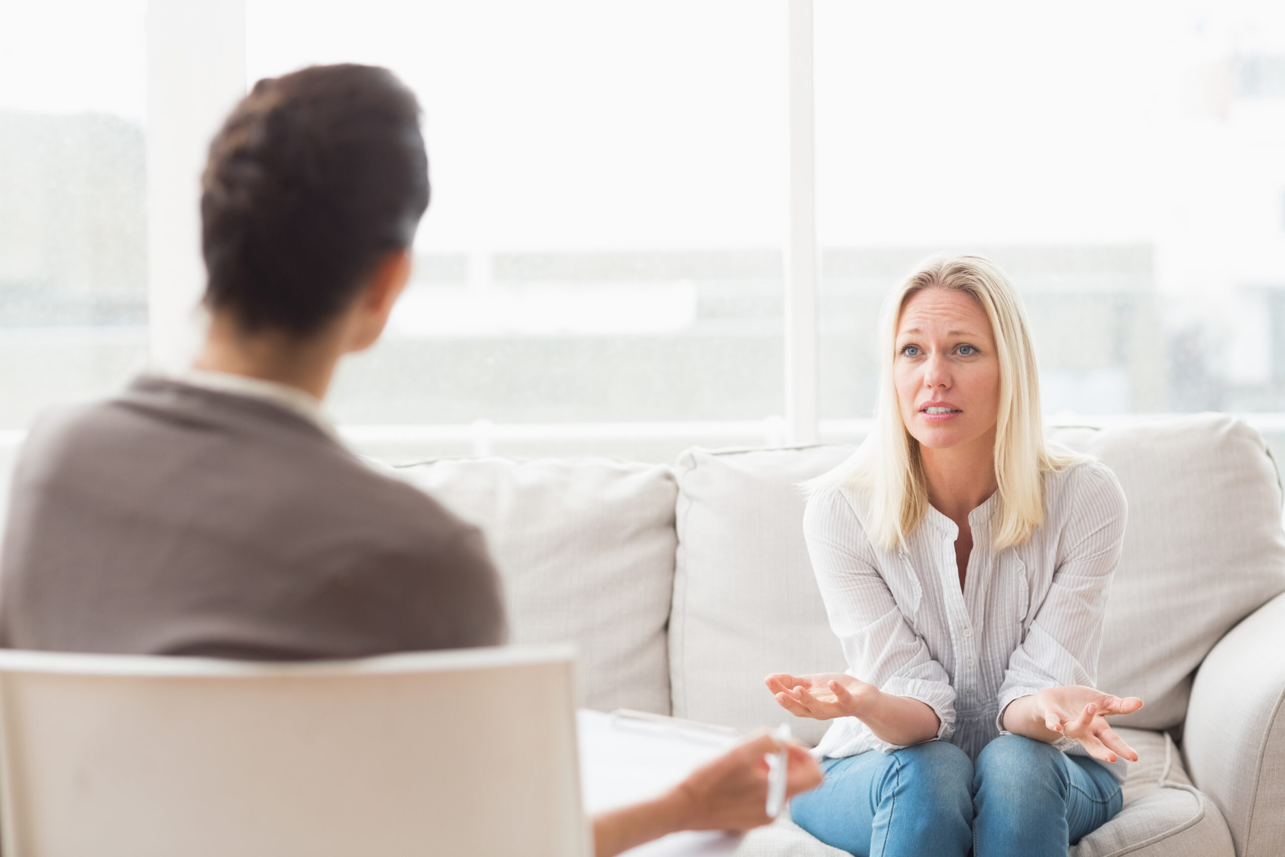 A woman with blonde hair is engaged in a discussion with a therapist